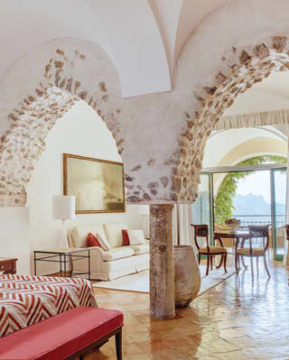 Spacious, light and airy hotel suite with exposed stone arches and red accents