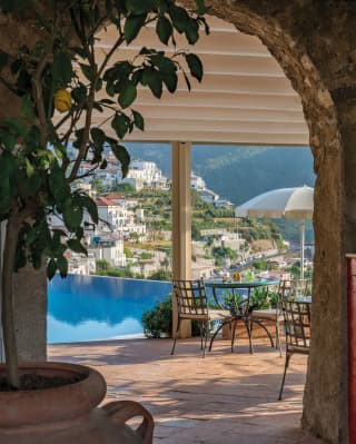 Strings of onion and garlic hang above a Ravello-tiled bar. A blue infinity pool leads the gaze to a hillside dotted with homes