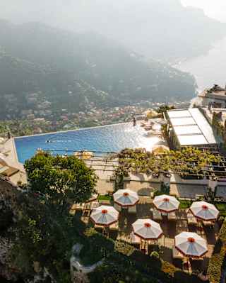 Six parasols offer shade to sun-loungers on a deck behind the pool which drops off into sublime coast views, seen from above.