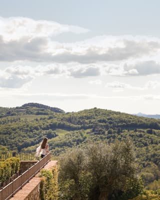 Lady standing at the edge of a raised terrace overlooking the Tuscan hills
