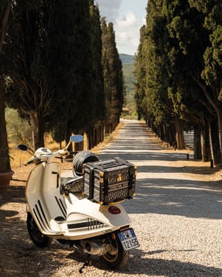 Dior Vespa is parked at a tree lined path
