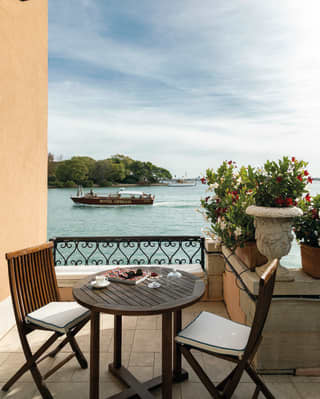 Hotel suite balcony with a breakfast table and chairs overlooking the Venetian Lagoon