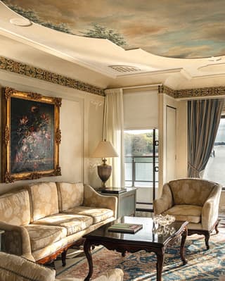 Hotel suite living room with a heavenly ceiling mural, plush furnishings and original oil paintings