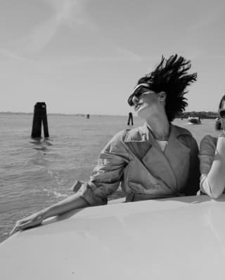 Dame mit Sonnenbrille, die auf einem fahrenden Motorboot posiert 