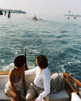 A couple looks over their shoulders at a Venetian Rowers as they take a ride across the water on the hotel’s teak launch
