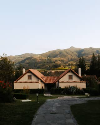 The olive-green rugged contours of the Andes rise behind a double-fronted casita with cream walls and a terracotta roof.