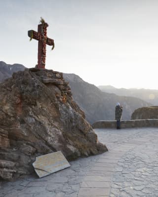 A cross on a rock, surrounded by a paved stone plateau overlooking a canyon
