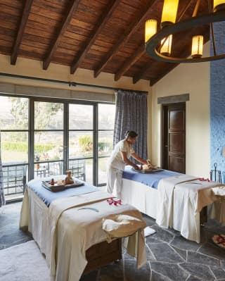 Spa therapist preparing a massage table in a luxuriously rustic treatment room