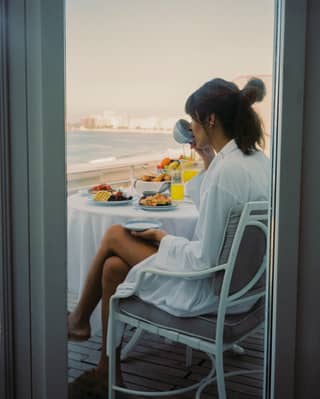 Lady relaxing with breakfast on a balcony overlooking Copacabana beach