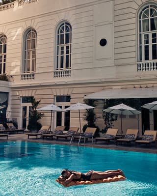 A woman in a black swimsuit resting on an airbed in the pool at the Copacabana Palace