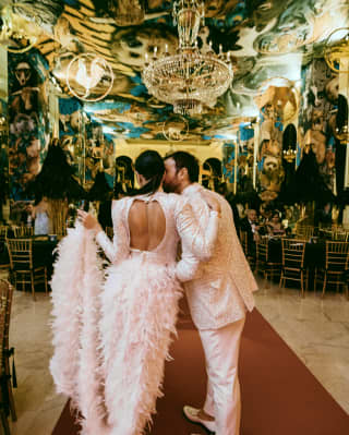 a man and woman in opulent clothing entering a grand ballroom together
