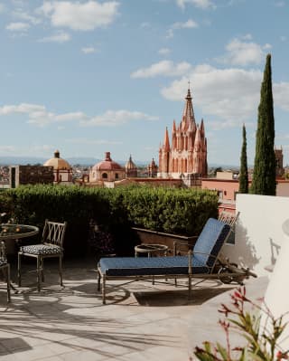 A table-set and a lounger enjoy stunning terrace views from Casa Limon over the city and Parroquia de San Miguel Arcangel.