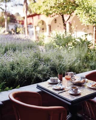 Table for two by a courtyard wall with flourishing lavender plants beyond