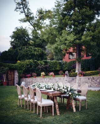 Outdoor banquet table in a garden with a full-length lily centrepiece