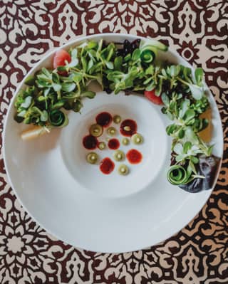 Birds-eye-view of a vibrant soup and salad dish against a patterned backdrop