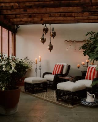 Two wicker chairs with foot stools await guests at the spa, serene with natural décor, candles, pendant lights and plants.