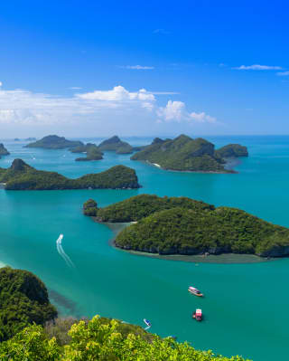 View over Mu Ko Ang Thong National Marine Park, where boats navigate the rash of lush islands that rise from the bold blue.