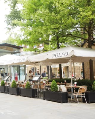 People walk past Polpo restaurant's al-fresco setting in Chelsea's Duke of York Square, near The Cadogan Hotel.