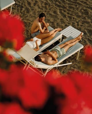 Top shot of three people lying on a sunbed on the beach