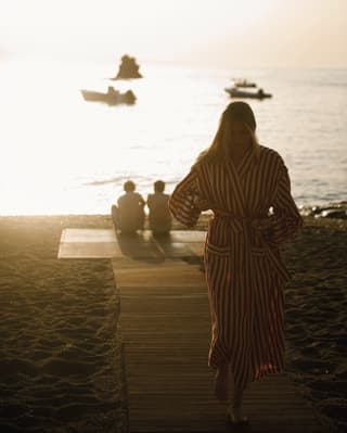 A lady with stripe coverup coming back from a sunset beach