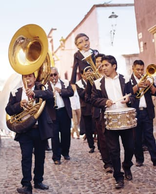 Traditional Mexican mariachi band marching down a cobbled road