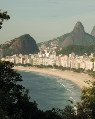Copacabana beach lined with white high-rises and towering mountains beyond