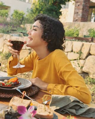 Woman laughing and drinking wine at El Encanto hotel alfresco dining table