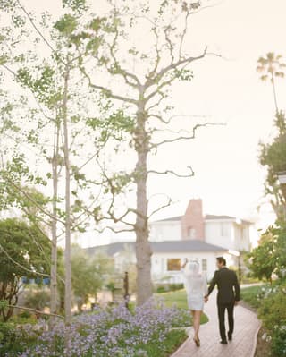 Bride and groom strolling along a red-brick path among hotel gardens