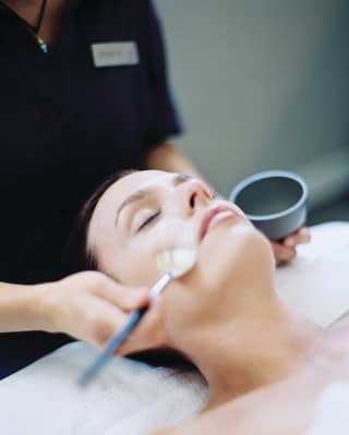 Close-up of a woman with closed eyes receiving a spa facial treatment