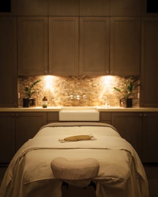 A spa treatment room in low light with spa table in the centre