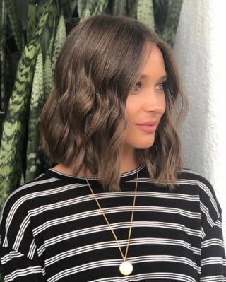 Dominique Fitzhugh, UK Sales Manager for Trains and Cruises, with mid-length brown hair, wears a black and white striped top.
