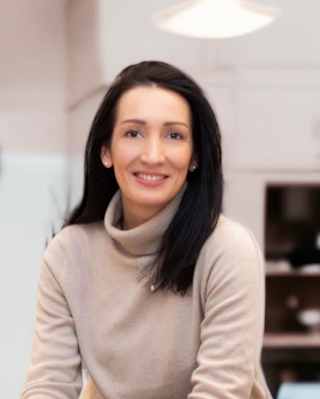 Eugénie Jason, General Manager of Les Bateaux Belmond, with mid-length black hair, smiles to camera in a beige roll-neck top.