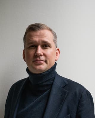 Portrait of Divisional Director Of Excellence for Southern Europe, Thomas Schwall wearing a dark suit over a black roll-neck.