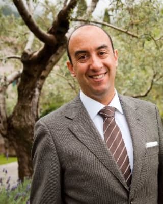 Ulisses Marreiros, General Manager of Copacabana Palace, wears a brown suit and tie, pictured in gardens, smiling to camera.
