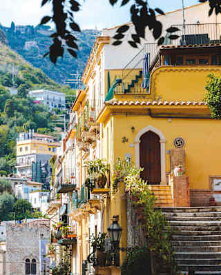 A blond woman in a strapless white dress enjoys a cream-stopped raspberry granita at Taormina's Bam Bam bar, in close-up.