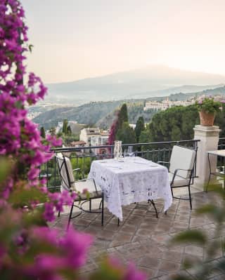 Table for two on an outdoor villa terrace with views across Taormina