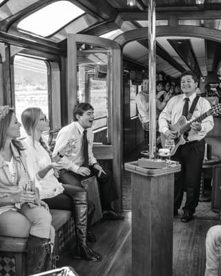 Guitar musicians playing to guests on a luxury train carriage