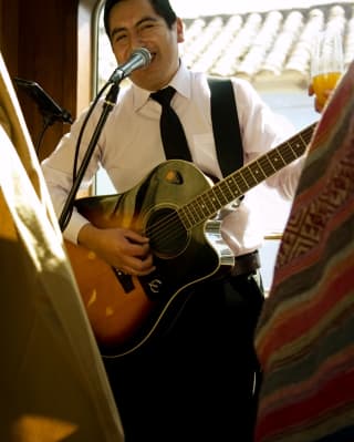 A musician smiling and playing guitar in the Hiram Bingham bar car