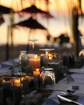 Close-up of glasses and silverware on a table with a candle centerpiece