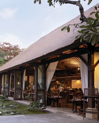 Open-air Balinese villa restaurant next to a lush pond brimming with lily pads