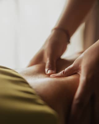 A masseuse presses her thumbs into the back of a guest at the Beach Spa, seen in a close-up of hands and skin.
