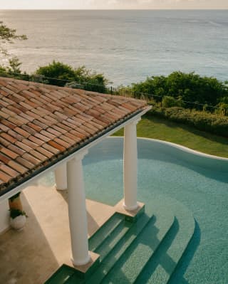 Aerial view of the terracotta-roofed veranda with column supports extending into the pool, with access steps on both sides.