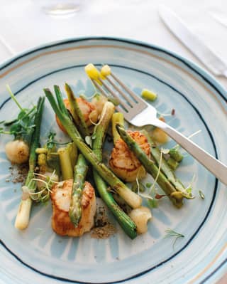 a close up of a dish with asparagus and scallops