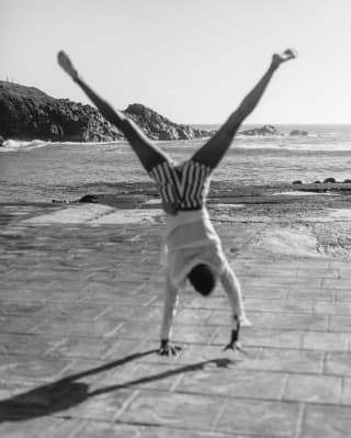 Black and white photo of a person somersaulting on a beach 