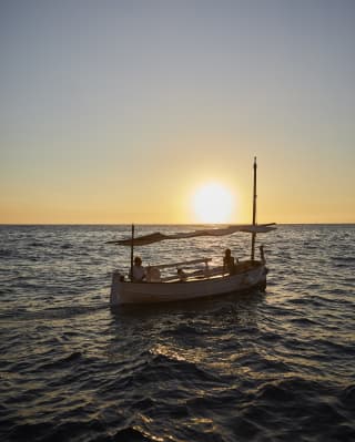 Sailing boat bobbing on waves at sunset