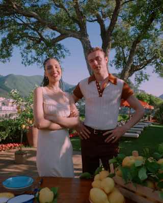 Influencer, Nara Smith and supermodel Lucky Blue Smith, stand at an outside table with bowls and crates of fresh lemons.