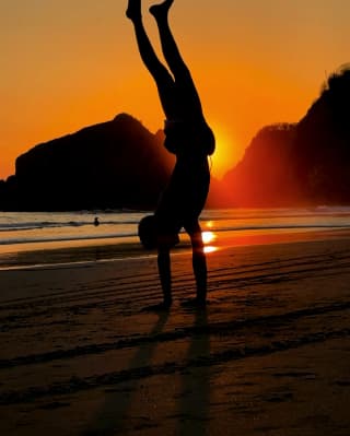 As the sun sets over Taormina's coast, Sam Youkilis captures a boy, silhouetted against the red sky, performing a handstand.