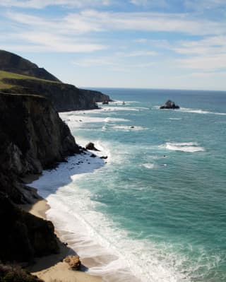 Frothy Pacific waves crash against rocks and cliffs on the sunny Santa Barbara coast