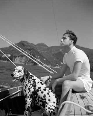 1936 black and white photo of a young man and a Dalmation dog on a sailing boat at sea near Portofino, by Herbert List.