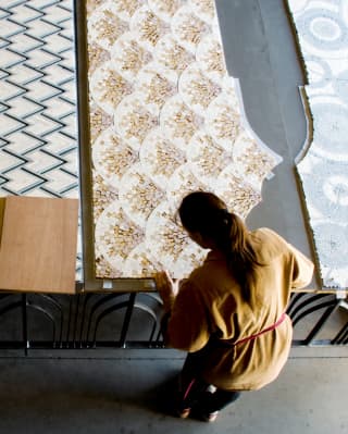 Seen from above, a craftswoman creates mosaic panels for the suites, with peacock, peaks, scallop and circle patterns.